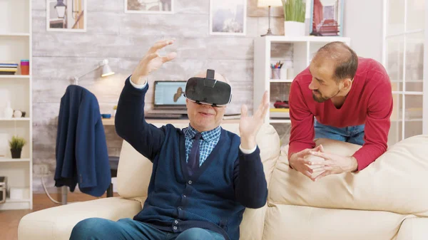 Nephew teaching his grandfather how to use virtual reality headset