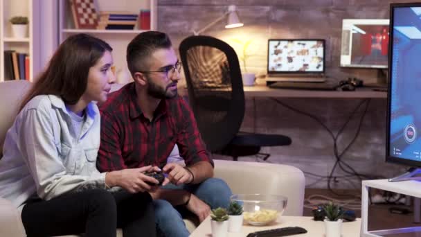 Mężczyzna siedzi na kanapie i uczy swoją dziewczynę grać w gry wideo — Wideo stockowe