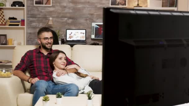 迷人的年轻夫妇一边看电影一边在沙发上放松 — 图库视频影像