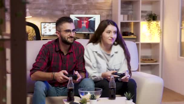 Radosna młoda para siedzi na parze i gra w gry wideo — Wideo stockowe