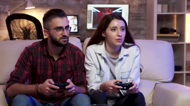 Pareja sentada en un sofá relajante jugando videojuegos — Vídeos de Stock