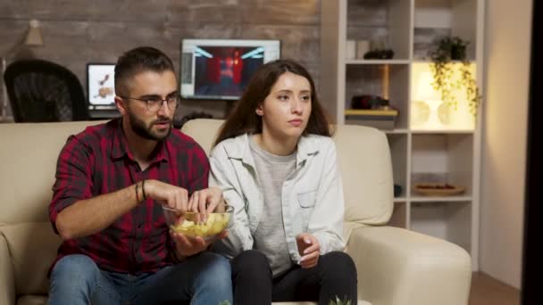 Kaukázusi fiatal pár eszik chipset tévézés közben — Stock videók