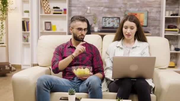 Happy young couple sitting on couch doing online shopping — Stock Video