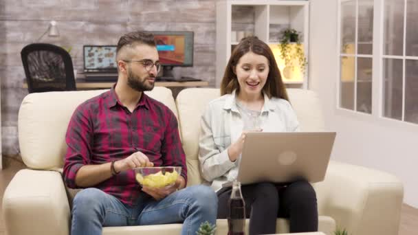Casal feliz no sofá comer batatas fritas — Vídeo de Stock