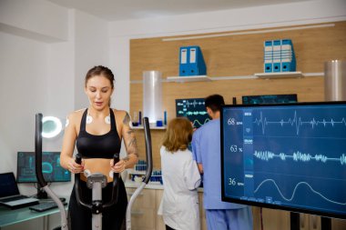 Adımları üzerinde fiziksel çaba sarfeden ve elektrotları ve kalp atışları olan bir bayan sporcu..