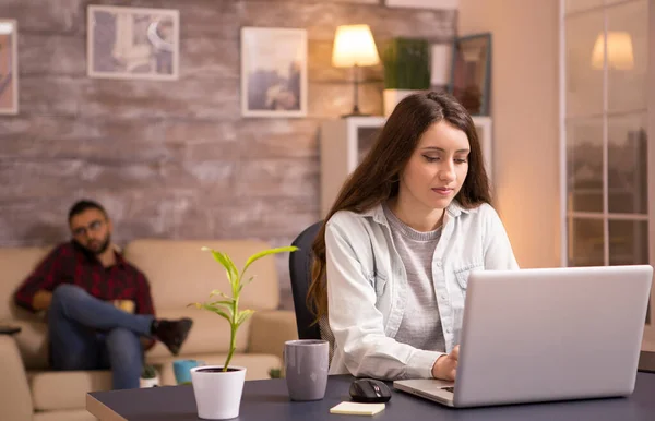 Jovem freelance feminino escrevendo e trabalhando no laptop na sala de estar — Fotografia de Stock