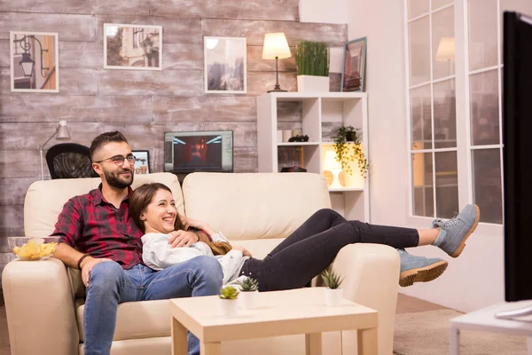 Bela jovem casal relaxante no sofá enquanto assiste a um filme na tv — Fotografia de Stock