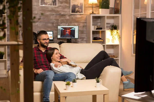 Adorável jovem casal relaxante no sofá e assistindo a um filme na TV — Fotografia de Stock