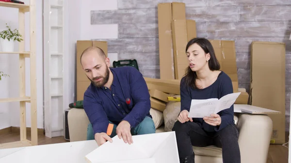 Couple assembling furniture using instructions in their new apartment