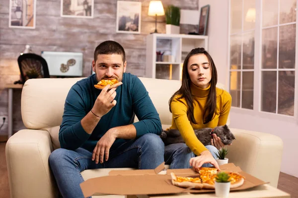 Hermosa pareja joven comiendo pizza mientras ve la televisión —  Fotos de Stock