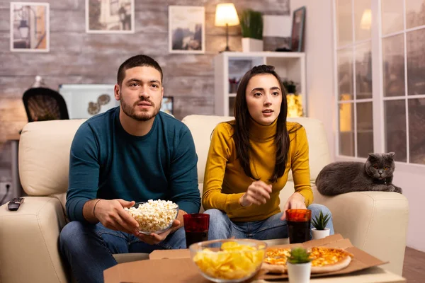 Belo jovem casal assistindo TV e comer fast food takeaway — Fotografia de Stock