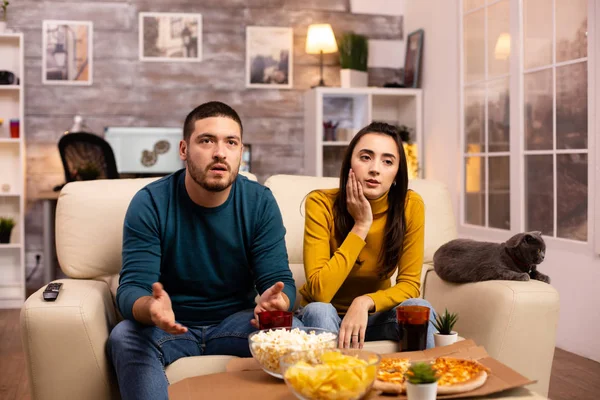 Glada par hejar på sitt favoritlag medan du tittar på Tv i vardagsrummet — Stockfoto