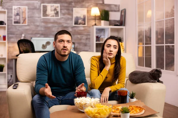 Casal feliz torcendo por sua equipe favorita enquanto assiste TV na sala de estar — Fotografia de Stock