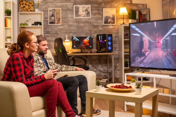 Casal jogando jogos de vídeo na TV de tela grande na sala de estar tarde da noite — Fotografia de Stock