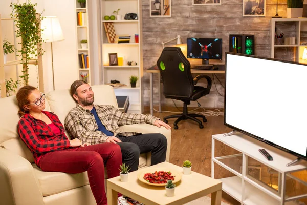 Пара смотрит на белый изолированный экран телевизора поздно ночью в гостиной — стоковое фото