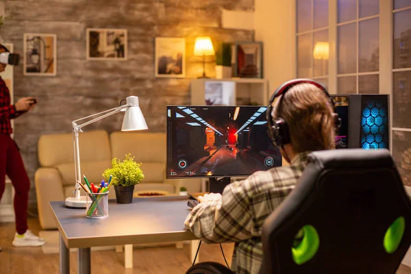 Visão traseira do jogador de vídeo profissional jogando no PC poderoso tarde da noite na sala de estar — Fotografia de Stock