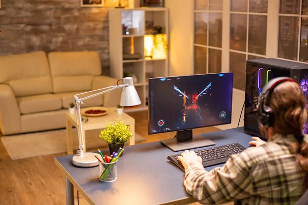 Visão traseira do jogador de vídeo profissional jogando no PC poderoso tarde da noite na sala de estar — Fotografia de Stock