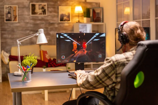 Pohled zezadu hráč muž hraje střelec na jeho výkonný PC počítač pozdě v noci v obývacím pokoji — Stock fotografie
