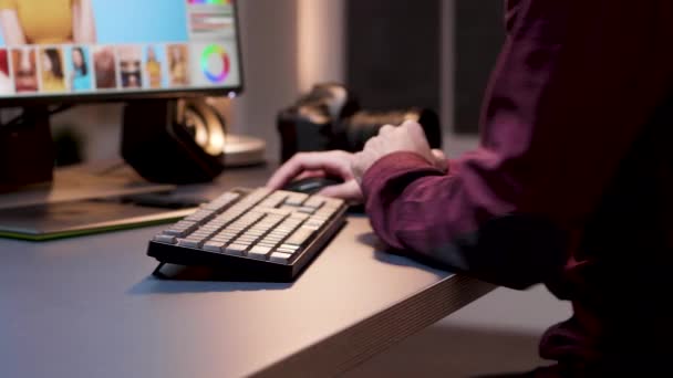 Nahaufnahme junger Fotograf mit Tastatur, um Fotos zu retuschieren — Stockvideo