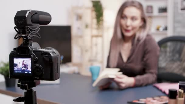 Vlogger haciendo una reseña de libro en fron de la cámara en su estudio creativo — Vídeos de Stock