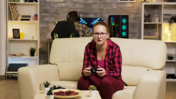 Mujer sentada en el sofá en la sala de estar jugando videojuegos — Vídeos de Stock