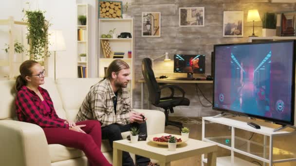 Χαρούμενη κοπέλα που μιλάει με το αγόρι της ενώ παίζει βιντεοπαιχνίδια — Αρχείο Βίντεο