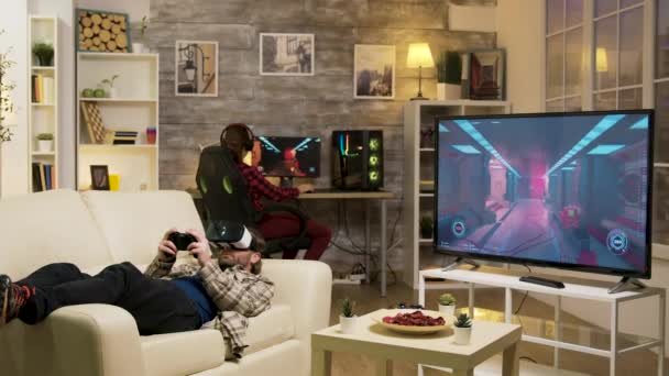 Hombre acostado en el sofá jugando videojuegos con auriculares vr — Vídeos de Stock