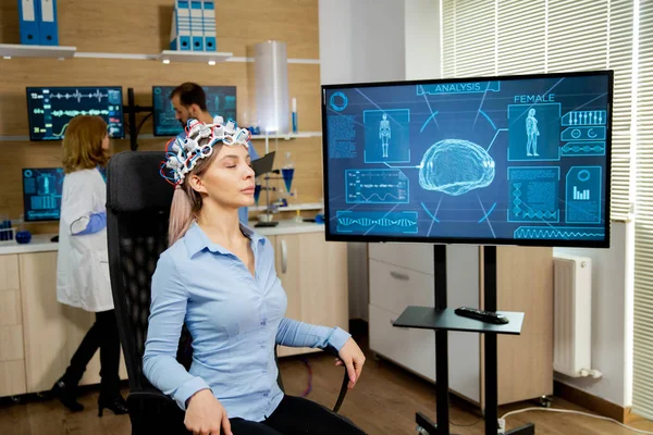 Patient woman who is brain scanned and his activity is shown on screen — 스톡 사진