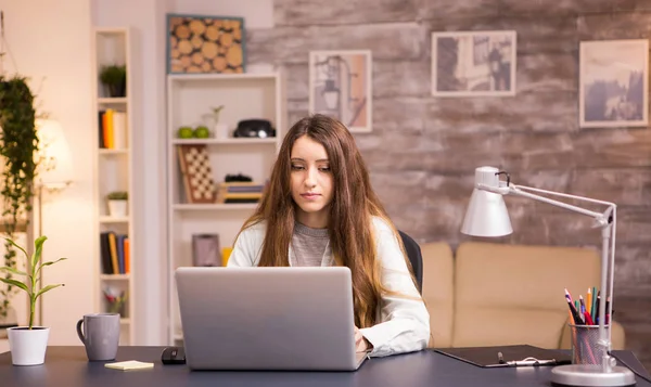Красива молода жінка працює на ноутбуці в домашньому офісі — стокове фото