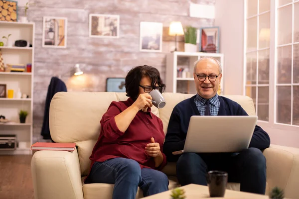 Elderly old couple using modern laptop to chat with their grandson