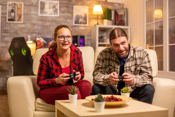 Пара геймерів грає в відеоігри по телевізору з бездротовими контролерами в руках — стокове фото