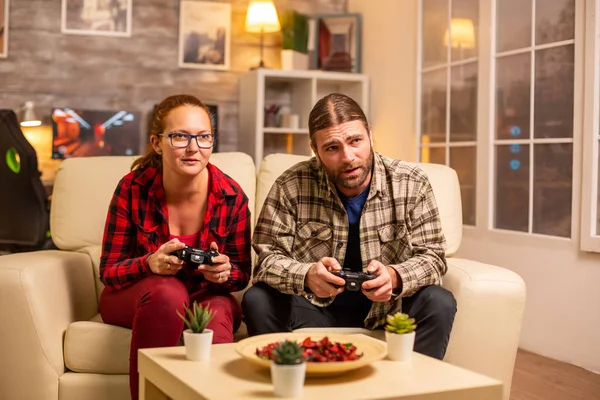 Gamers couple playing video games on the TV with wireless controllers in hands