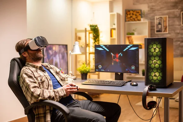 Homem jogador profissional usando fone de ouvido VR para jogar no PC poderoso — Fotografia de Stock