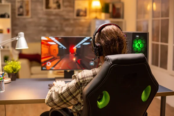 Vista posterior de jugador masculino jugando un tirador en su computadora de gran alcance de la PC tarde en la noche en la sala de estar — Foto de Stock