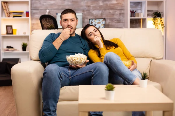 Hezký pár doma jíst popcorn a dívat se na televizi — Stock fotografie