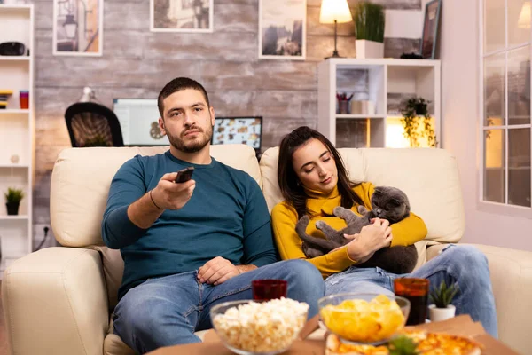 Красивая молодая пара смотрит телевизор и ест фаст-фуд — стоковое фото