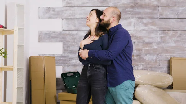 Feliz jovem casal abraçando uns aos outros em seu novo apartamento — Fotografia de Stock