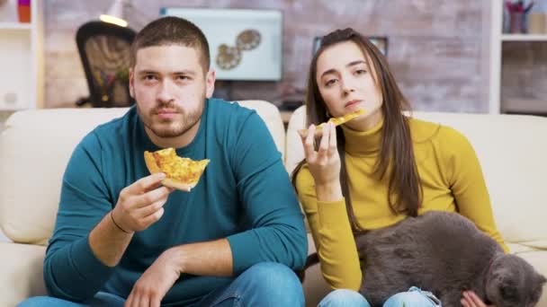 Jeune couple assis sur le canapé regarder la télévision — Video