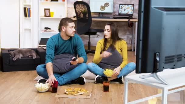 Couple assis sur le sol regarder la télévision — Video