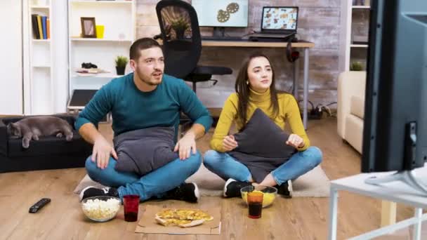Νεαρό ζευγάρι που κάθεται στο πάτωμα και ζητωκραυγάζει — Αρχείο Βίντεο