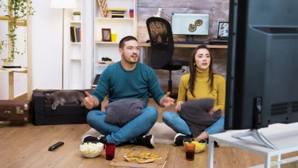 白人の若いカップルがリビングルームの床に座っています — ストック動画