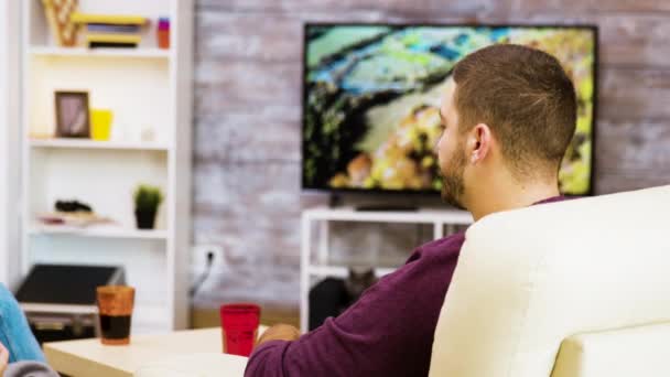 Back view of young man sitting on chair eating popcorn — Stockvideo