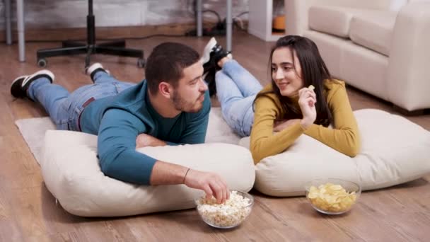 Молодая женщина улыбается его парню во время просмотра телевизора — стоковое видео