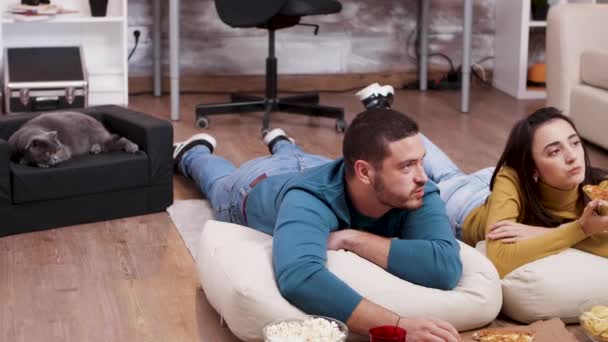 Mladý muž a žena leželi na podlaze a dívali se na televizi — Stock video