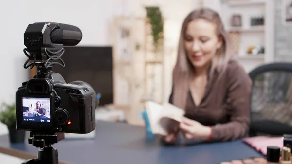 Vlogger haciendo una reseña de libro en fron de la cámara en su estudio creativo — Foto de Stock