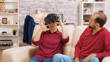 Yeğen büyükannesine sanal gerçeklik kulaklığını nasıl kullanacağını öğretiyor.
