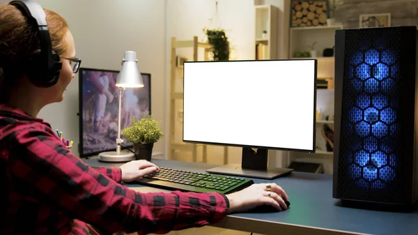 Женщина в наушниках играет в игры на компьютере в гостиной — стоковое фото