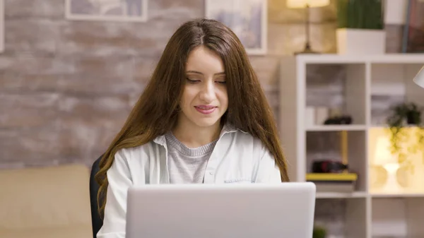 Menina sorrindo enquanto trabalhava no laptop na sala de estar — Fotografia de Stock
