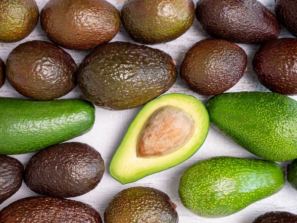 Mezcla de aguacates rasgados y verdes sobre tabla de madera blanca — Foto de Stock