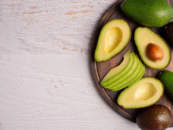 Vista superior de aguacate fresco cortado sobre tabla de madera blanca — Foto de Stock